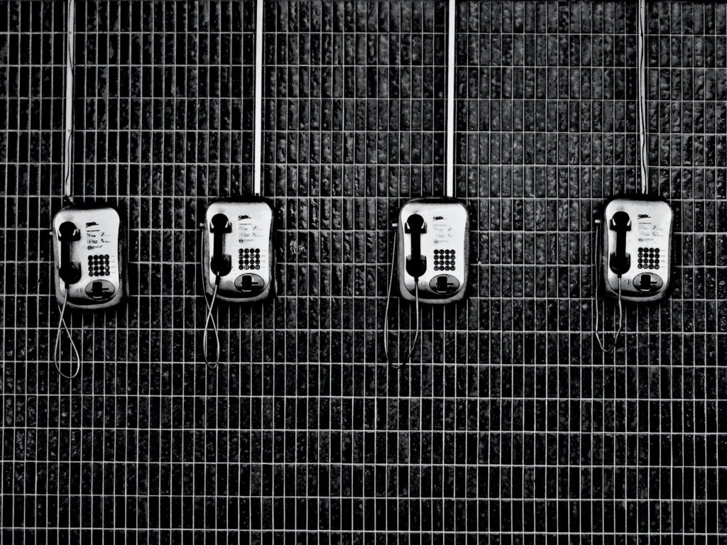 bank of phones mounted on black wall at prison