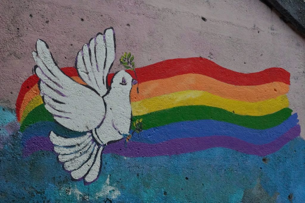 A mural of a dove in front of a rainbow, repesenting religion and LGBTQIA pride