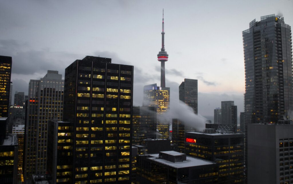 The Toronto skyline on an overcast day with wisps of cloud drifting between the CN Tower and office buildings, representing Best Law Firms Canada.