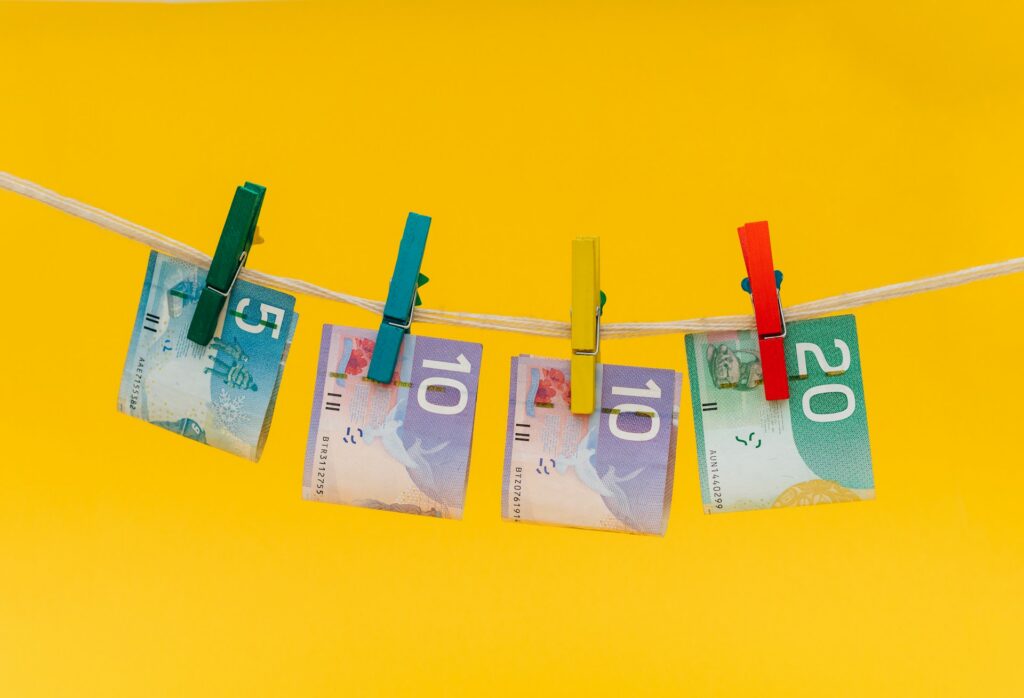 Five, ten, and twenty-dollar bills clipped to a string with coloured laundry pins, representing a financial crimes agency in Canada.