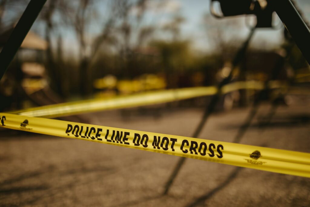 Yellow police tape is wrapped around a blurred structure outdoors, representing disclosure of police misconduct records.